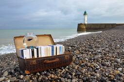 Valise de livres sur plage de galets