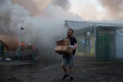 Un homme transporte des cartons contenant des objets récupérés sur le marché aux livres ravagé par un incendie